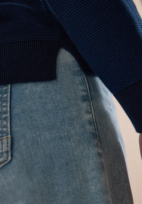 Pull bicolore à col en V urban dark blue Gros plan d’un pull en maille bleu porté sur un jean clair.