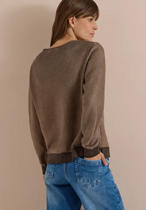 Pullover im Two-Tone-Look mit V-Neck truffle brown Frau von hinten trägt braunen Pullover und blaue Jeans vor beigem Hintergrund.