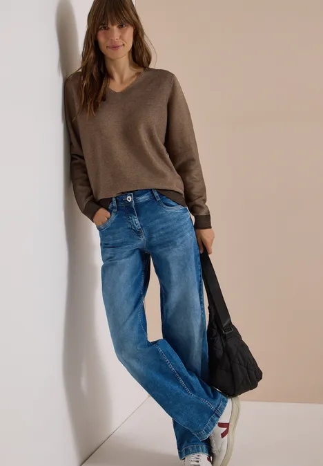 Pullover im Two-Tone-Look mit V-Neck truffle brown Frau mit braunem V-Pullover, blauen Jeans und schwarzer Tasche lehnt entspannt an der Wand.