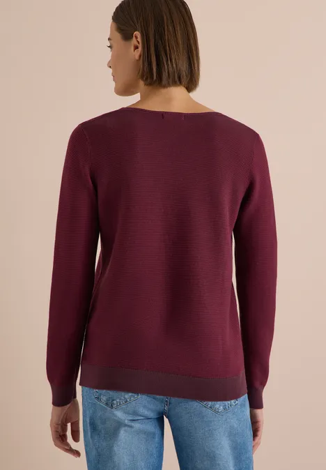 Pull bicolore à col en V berry red Femme vue de dos portant un pull fin bordeaux et un jean bleu clair.