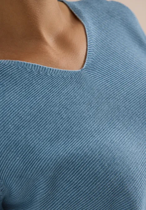 Pullover im Two-Tone-Look mit V-Neck mountain air blue Nahaufnahme eines Oberkörpers in hellblauem Rippstrick-V-Ausschnittpullover.