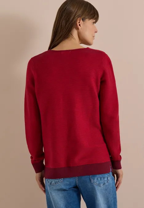 Pullover im Two-Tone-Look mit V-Neck flame red Frau von hinten in rotem Pullover und blauen Jeans.