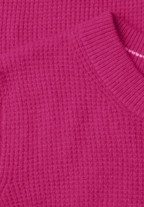 Close-up van een fuchsia gebreide trui met wafelpatroon en ronde hals