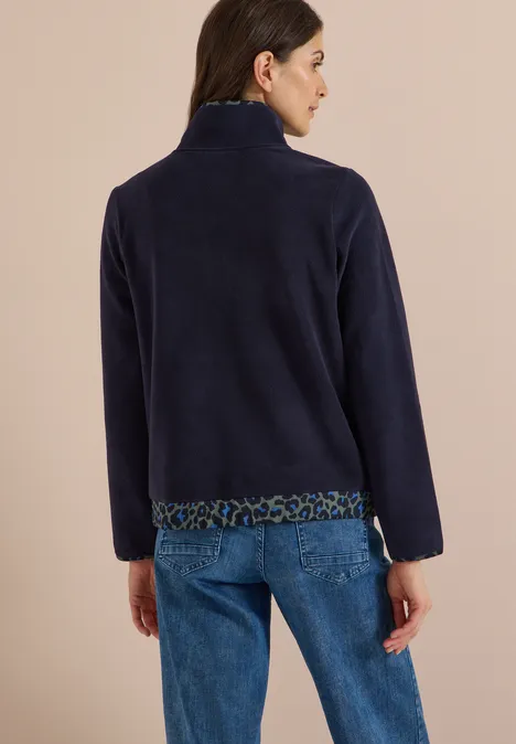 Fleecetrui met leopardetails urban dark blue Vrouw van achteren in marineblauwe fleecetrui met luipaardprintbies en spijkerbroek, beige achtergrond