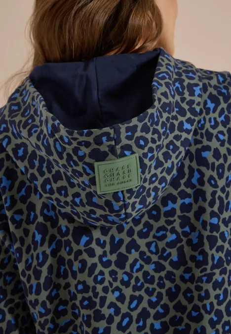 Graue Kapuzenjacke mit blauem Leopardenmuster und dunkelblauem Innenfutter, grünem Label am Rücken.