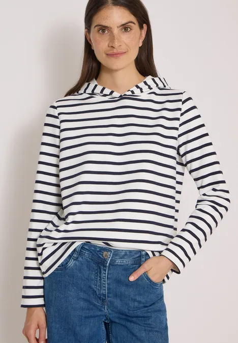 Sweatshirt mit Kapuze und Streifen vanilla white Junge Frau in weiß-blau gestreiftem Hoodie, Jeans, lächelt, halb in die Tasche gesteckte Hand.