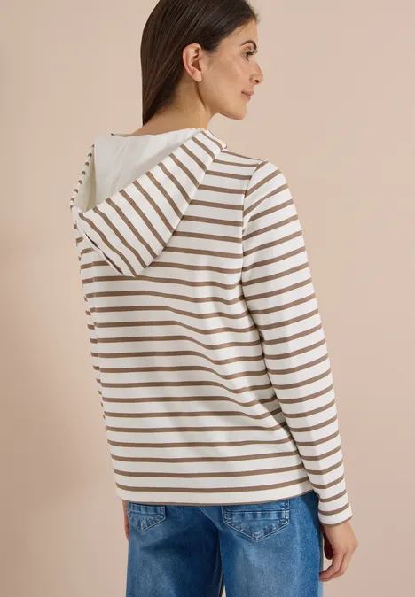 Sweatshirt mit Kapuze und Streifen natural taupe Frau trägt beige-weiß gestreiften Hoodie und blaue Jeans, seitliche Ansicht vor neutralem Hintergrund.