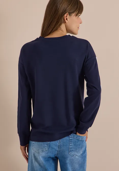 Sweatshirt mit Rundhals und Tapedetails urban dark blue Frau von hinten, trägt dunkelblaues Langarmshirt und blaue Jeans, Hände in den Hosentaschen.