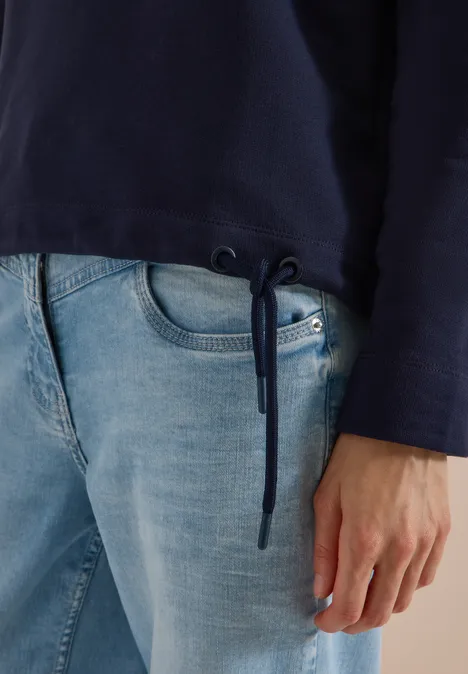 Sweatshirt mit Wording und Tunnelzug urban dark blue Dunkelblauer Pullover mit Kordelzug am Saum, dazu helle Jeans, Hand am Oberschenkel.
