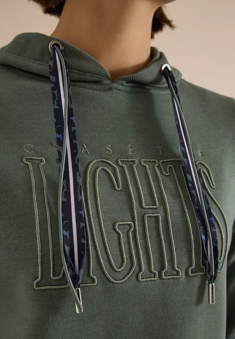 Sweatshirt mit Kapuze und Wording dried olive green Grüner Hoodie mit geprägtem ‚CHASE LIGHTS‘-Schriftzug und gemusterten Kordeln, nur Oberkörper sichtbar.