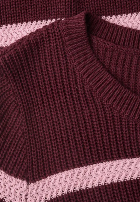 Nahaufnahme eines gestrickten Pullovers in Bordeauxrot mit rosa Querstreifen.