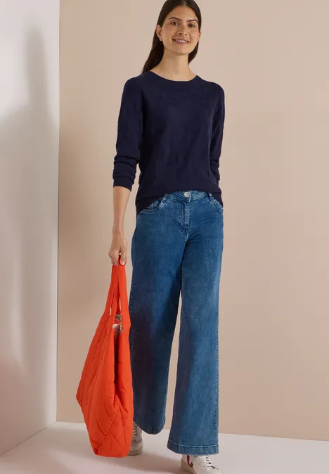 Trui met boothals en structuur urban dark blue Vrouw in donkerblau trui, wijde spijkerbroek met een rode tas.