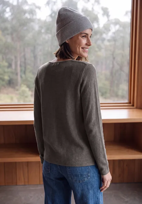 Langarm Pullover mit Rundhals und Struktur mushroom taupe melange Frau mit grauem Pullover und Mütze steht lächelnd vor großen Fenstern.