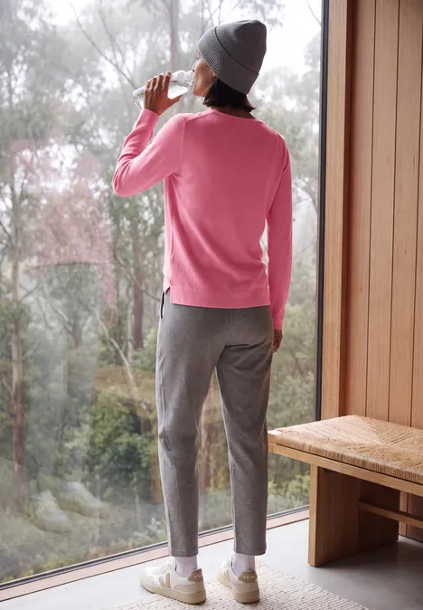 Langarm Pullover mit Rundhals und Struktur dark blossom melange Eine Person in rosa Pullover, grauer Mütze und Hose steht an einem Fenster und trinkt aus einer Tasse.