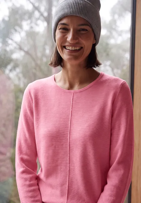 Langarm Pullover mit Rundhals und Struktur dark blossom melange Junge Frau in rosa Pullover und grauer Mütze, die vor einem Fenster lächelt