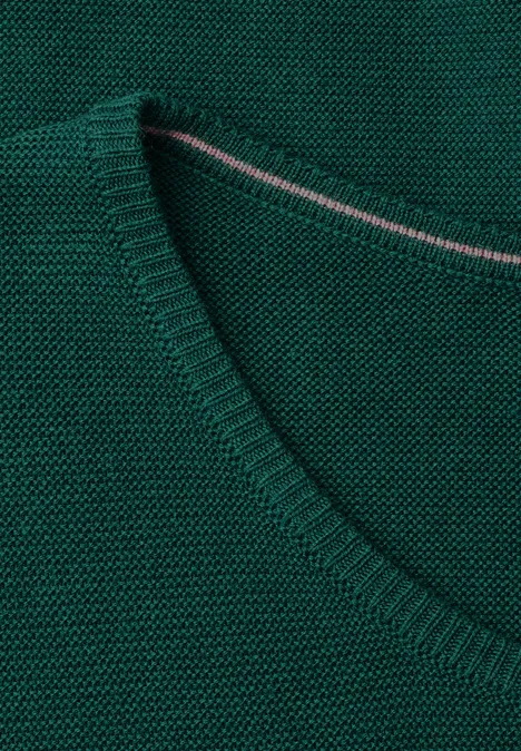 Nahaufnahme eines grünen, fein gestrickten V-Ausschnitt-Pullovers