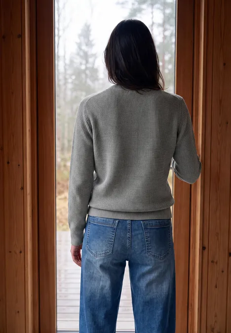 Pullover mit Rundhals und Struktur sporty grey melange Person mit grauem Pullover und blauen Jeans blickt von einer Holztür aus in den herbstlichen Wald.