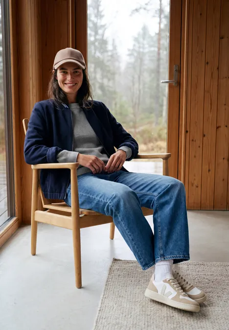 Pullover mit Rundhals und Struktur sporty grey melange Junge Person in Baseballkappe und Brille sitzt entspannt auf Holzstuhl in gemütlicher Hütte.