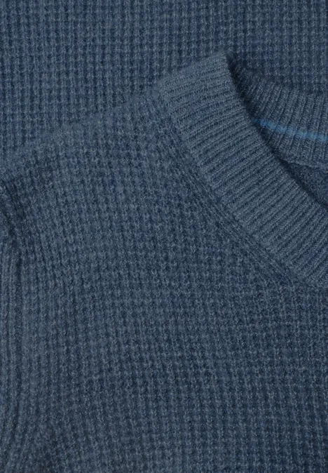 Nahaufnahme eines dunkelblauen Strickpullovers mit Waffelstruktur.