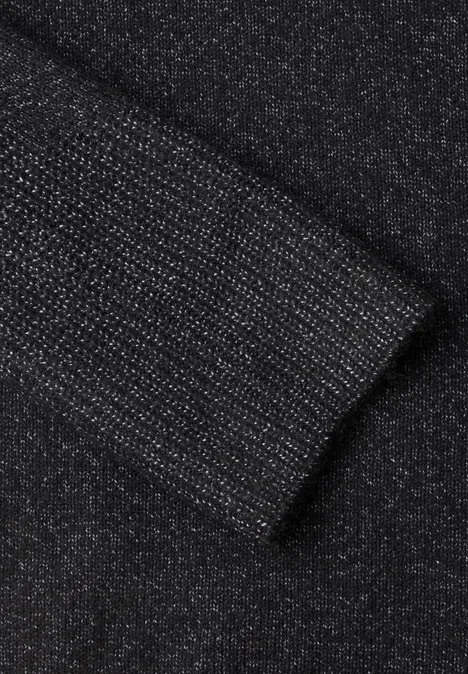 Nahaufnahme eines schwarzen, glitzernden Strickstoff-Ärmels mit Bündchen.