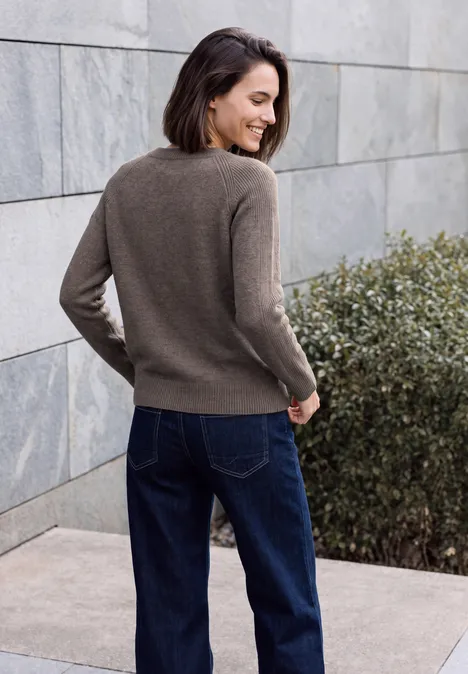 Pullover mit Rundhals und Strukturmix mushroom taupe melange Frau in braunem Pullover und Jeans steht an einer grauen Steinwand, blickt lächelnd über die Schulter.