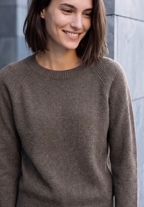 Pullover mit Rundhals und Strukturmix mushroom taupe melange Eine lächelnde Frau in braunem Pulli vor einer Steinwand.