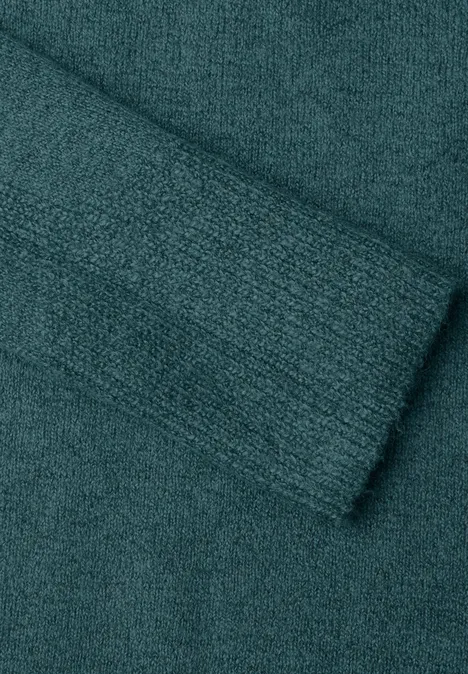Grob gestrickter, gefalteter Stoff in dunklem Türkis