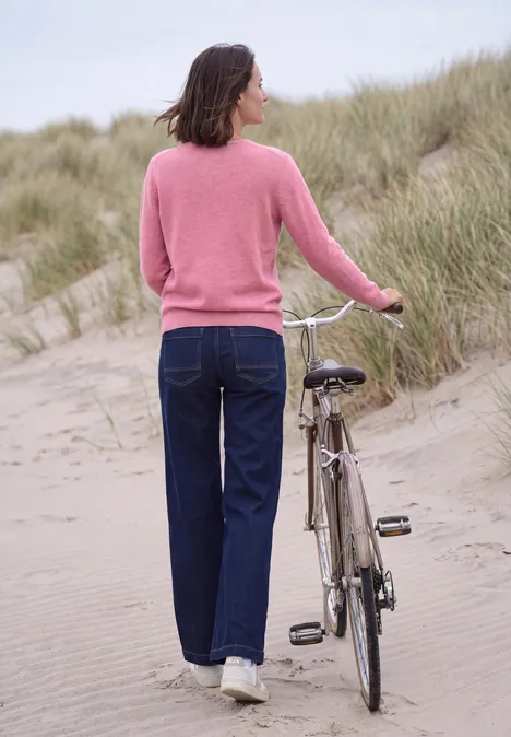 Langarm Pullover mit V-Neck dark blossom melange Frau von hinten schiebt Fahrrad über Dünen am Strand.