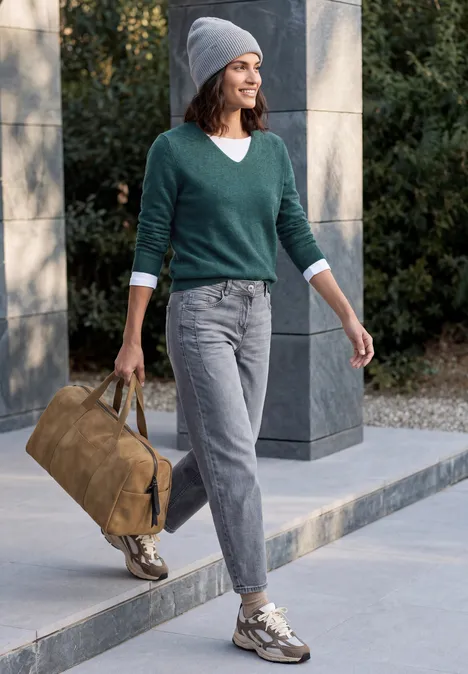 Langarm Pullover mit V-Neck dark sea green melange Eine Frau spaziert draußen mit grauer Jeans, grünem Pullover, Mütze und Tasche.