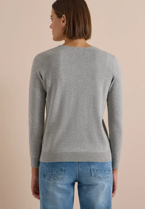 Basic Pullover mit V-Neck in Unifarbe mineral grey melange Frau von hinten in grauem Pullover und blauen Jeans vor beigem Hintergrund.
