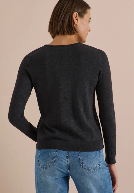 Pull couleur unie à col en V charcoal grey melange Vue de dos d'une femme portant un pull noir et un jean bleu sur fond clair.