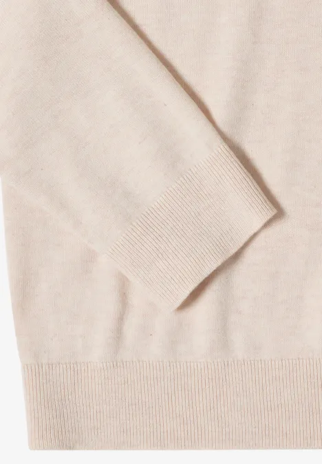 Close-up van een lichtbeige gebreide trui met geribbelde manchetten en fijne structuur