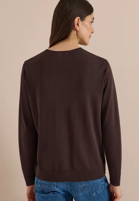Eenvoudige trui met V-hals in effen kleur truffle brown Vrouw van achteren in een bruine trui en blauwe jeans tegen een neutrale achtergrond.