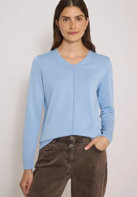 Eenvoudige trui met V-hals in effen kleur easy blue Vrouw draagt lichtblauwe V-hals trui en bruine broek voor een neutrale achtergrond.