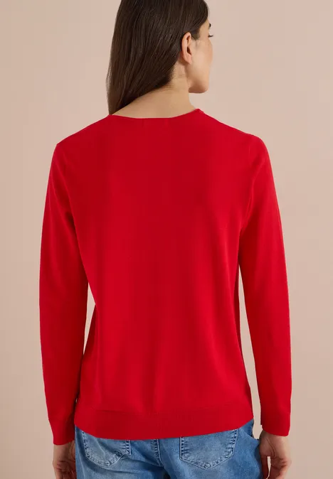Eenvoudige trui met V-hals in effen kleur flame red Vrouw van achteren met een rode trui en spijkerbroek.