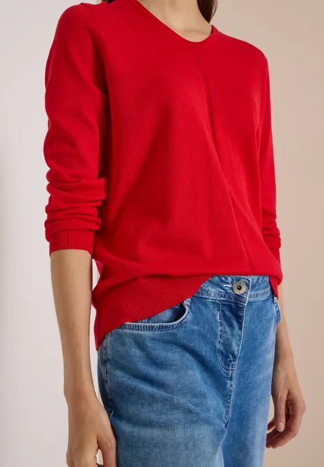 Eenvoudige trui met V-hals in effen kleur flame red Iemand draagt een rode trui en blauwe spijkerbroek, alleen torso en armen zichtbaar.