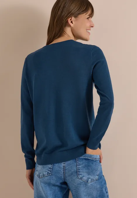 Basic Pullover mit V-Neck in Unifarbe moonlight blue Frau von hinten in dunkelblauem Pullover und Jeans, Hände in den Taschen.