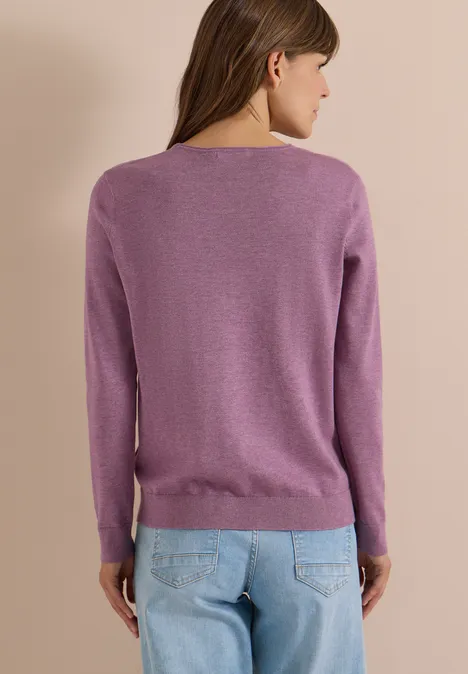 Frau von hinten, trägt einen violetten Pullover und blaue Jeans.
