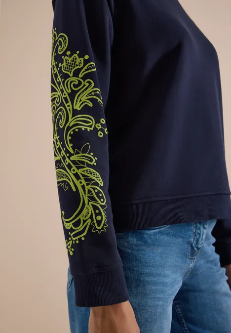 Sweatshirt mit Artwork am Ärmel urban dark blue Damenpullover in dunkelblau mit neon-grünem Paisley-Muster auf dem Ärmel, kombiniert mit Jeans