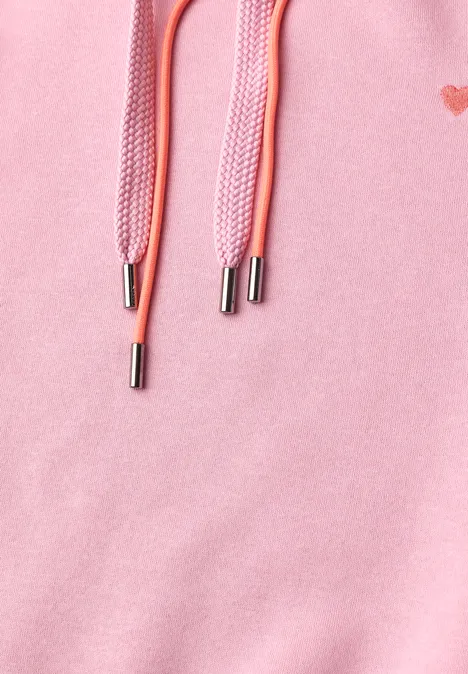 Gros plan d'un sweat rose avec cordons et embouts métalliques argentés.