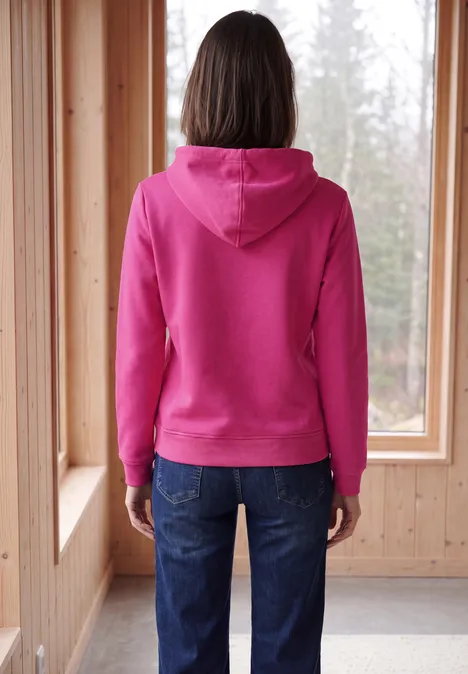 Langarm Sweatshirt mit Kapuze pink flash Rückansicht einer Person im pinken Kapuzenpullover, vor einem Fenster in einem Holzraum.