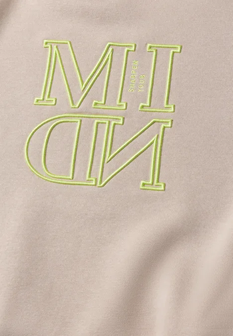 Beige Stoff mit neongrüner Aufschrift 'MIND', wobei 'ND' spiegelverkehrt dargestellt ist.