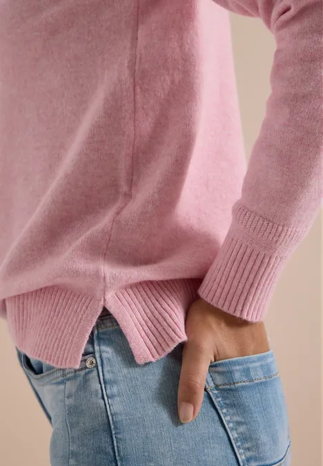 Trui met lange mouwen en polokraag mellow rose melange Persoon in een roze trui en blauwe spijkerbroek, hand in achterzak, zijaanzicht.