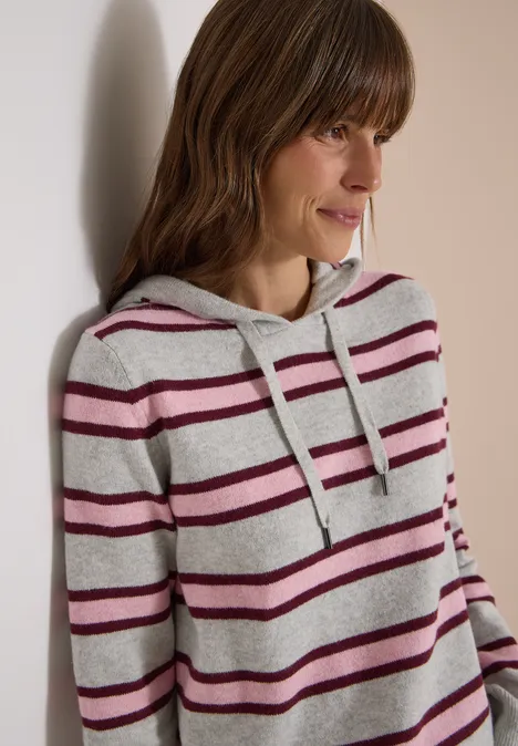 Trui met lange mouwen, capuchon en strepen light grey melange Vrouw leunt tegen muur, draagt lichtgrijze hoodie met bordeauxrode strepen.