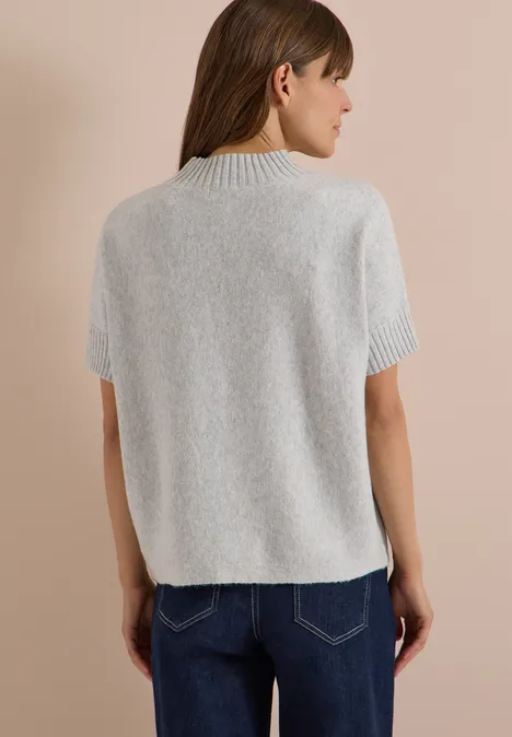 Dolman-trui met col light grey melange Rückenansicht einer Frau in grauem Kurzarm-Pullover mit hohem Kragen und blauer Jeans.