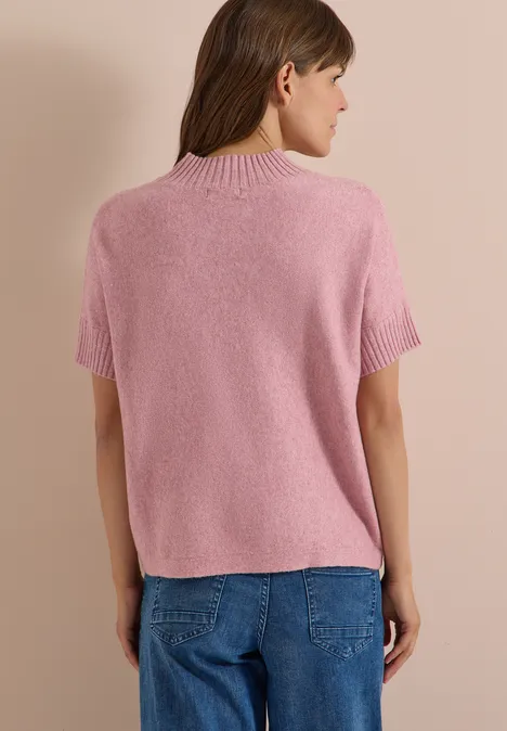 Dolman-trui met col velvet rose melange Rückansicht einer Frau in rosa kurzärmligem Pullover und blauer Jeans vor hellbraunem Hintergrund.