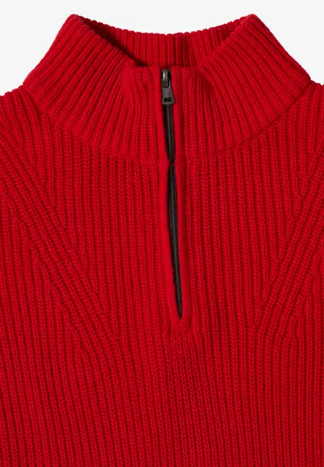 Ein roter, grob gestrickter Pullover mit hohem Kragen und kurzem Front-Reißverschluss.