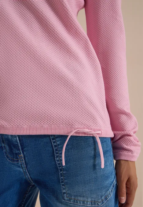 Rosa langärmeliges Oberteil mit Kordelzug am Saum, kombiniert mit blauen Jeans.