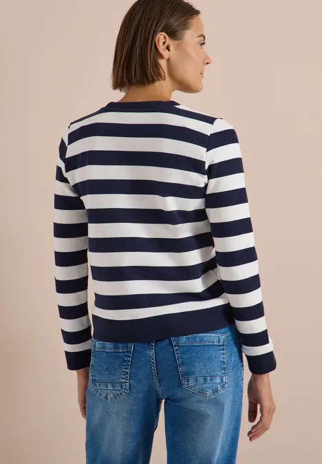 Sweatshirt mit Rundhals und Streifen urban dark blue Frau von hinten in weiß-blau gestreiftem Pullover mit langen Ärmeln und Jeans vor beigem Hintergrund.