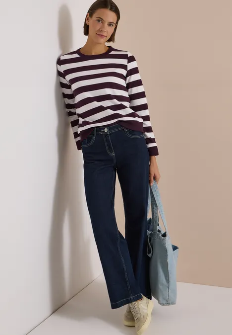 Sweatshirt mit Rundhals und Streifen eggplant red Frau lehnt an Wand, trägt gestreiften Pullover, weite Jeans und hält eine hellblaue Tasche.